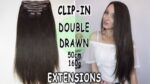 Clip-in hajhosszabbítás, 50 cm hosszú, 160g súlyú, dupla szálú, barna színű hajtincsekkel és mosolygó nővel fehér felsőben.